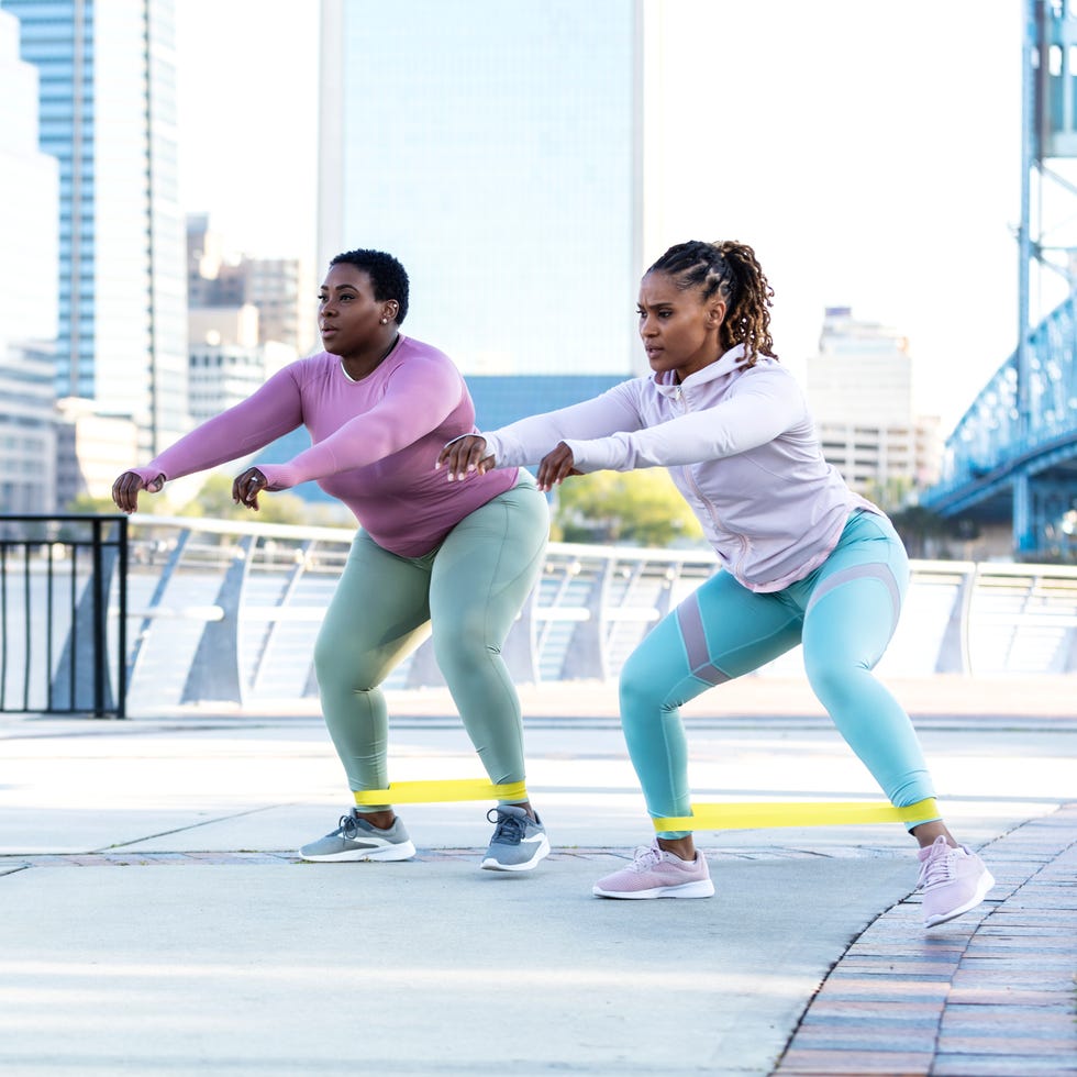 two african american women in city park, do jump squats