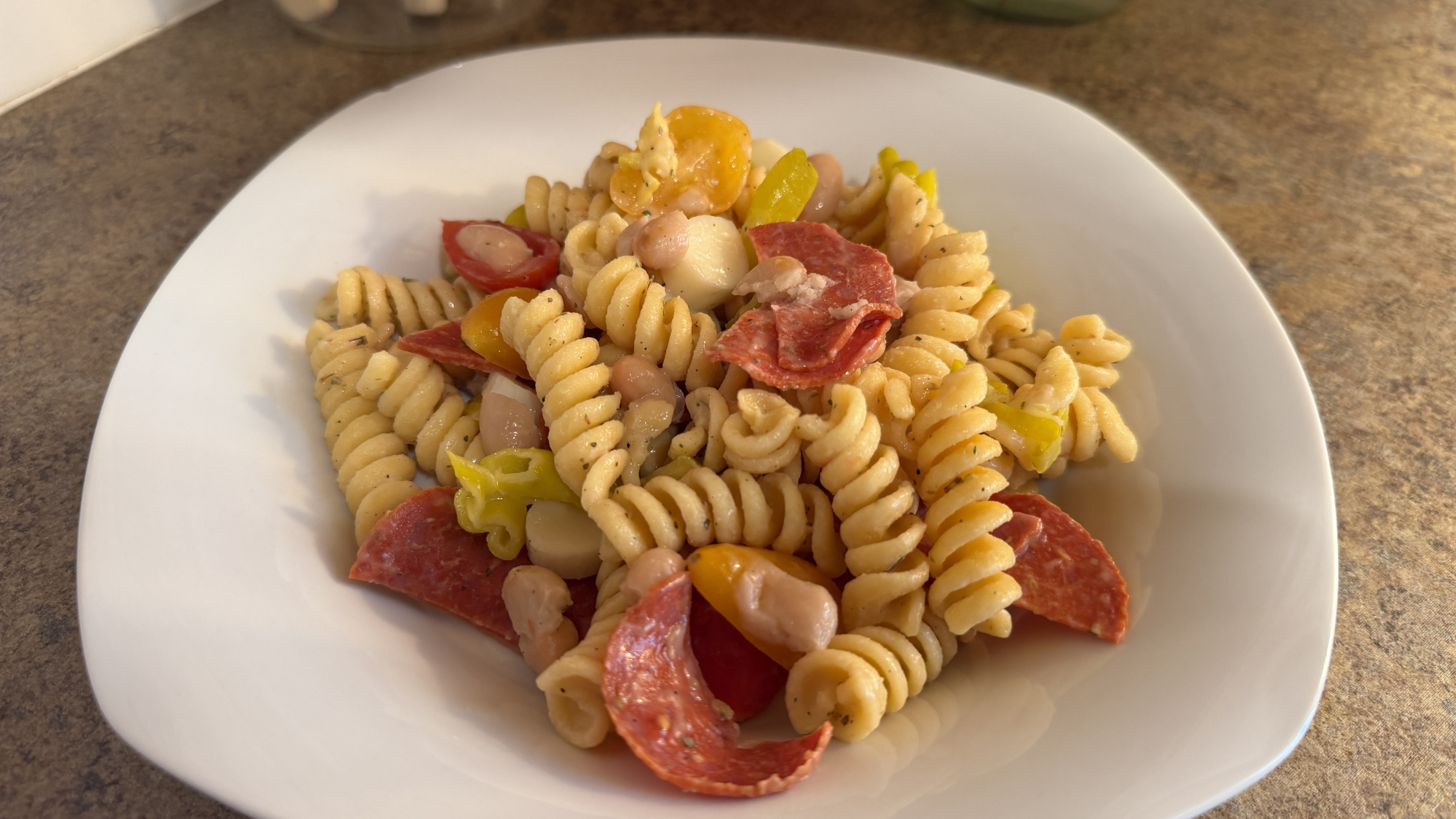 Plate of pasta with pepperoni slices and mozzarella balls