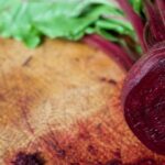 A vibrant, freshly cut beetroot lies on a rustic wooden cutting boa…