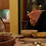 In the soft afternoon light of a cozy dining room, a 71-year-old ma…